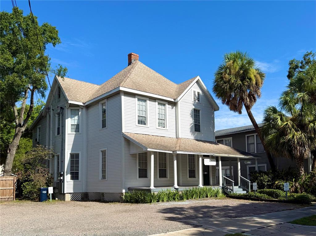 A two-story white wood-sided house with a front porch stands beside a palm tree — 311 S BREVARD AVENUE, TAMPA, FL