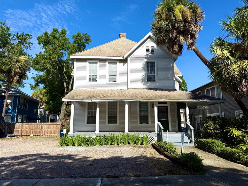 A two-story house with light gray siding, a front porch, and a gravel driveway — 311 S BREVARD AVENUE, TAMPA, FL
