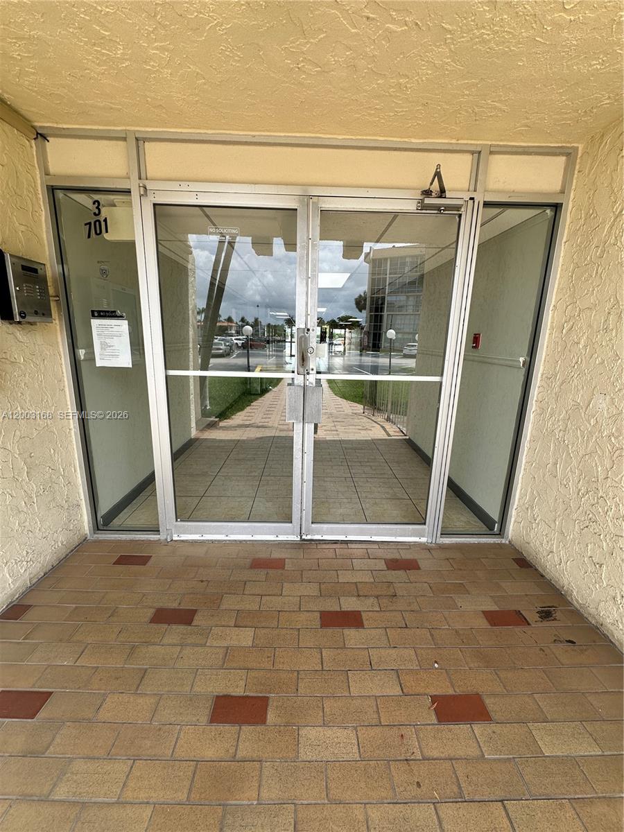 A set of glass double doors leads into a building entrance with tiled flooring — 701 Three Islands Blvd # 110, Hallandale Beach FL 33009, HALLANDALE BEACH, FL