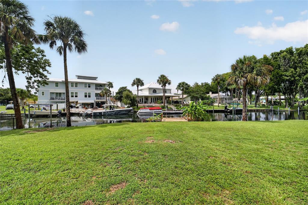 A grassy lawn overlooks a canal with several houses and boats in the background — 232 SE KINGS BAY DR, CRYSTAL RIVER, FL