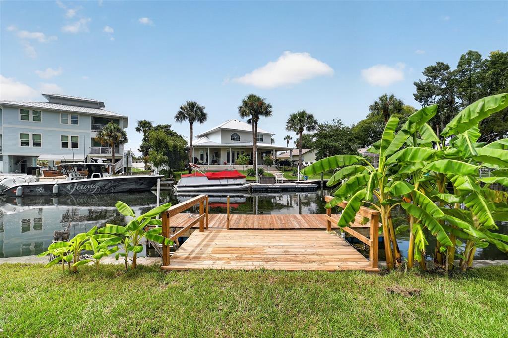 A wooden dock extends into a canal with boats and houses in the background — 232 SE KINGS BAY DR, CRYSTAL RIVER, FL