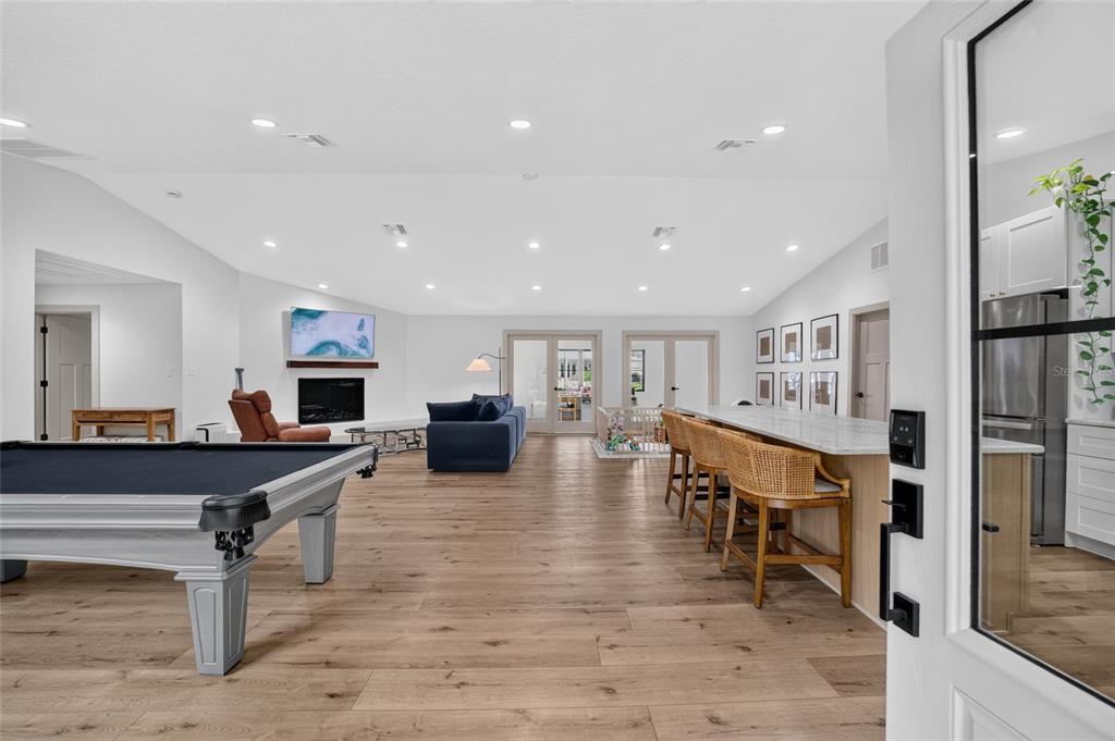 A spacious open-concept living area features a pool table, kitchen island with seating, and fireplace — 232 SE KINGS BAY DR, CRYSTAL RIVER, FL