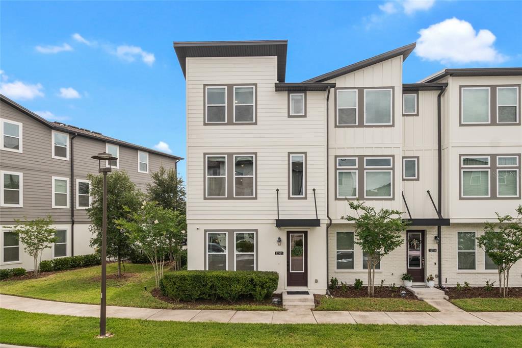 A three-story townhouse with white siding and a dark brown front door — 12551 WILLSTATTER AVENUE, ORLANDO, FL