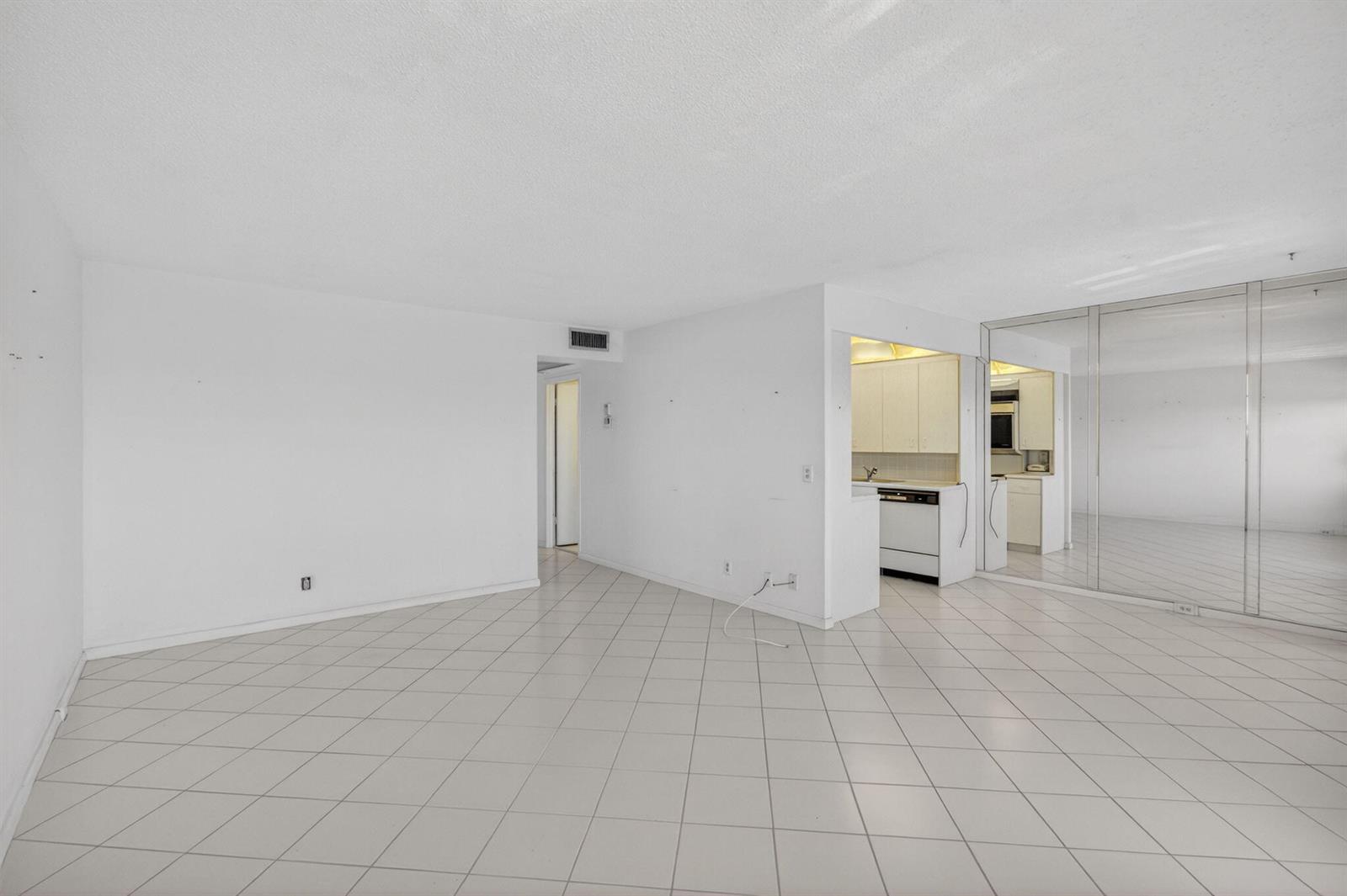 An open-concept living area features white tile flooring, white walls, and a pass-through kitchen — 4059 Guildford D, Boca Raton FL 33434, BOCA RATON, FL