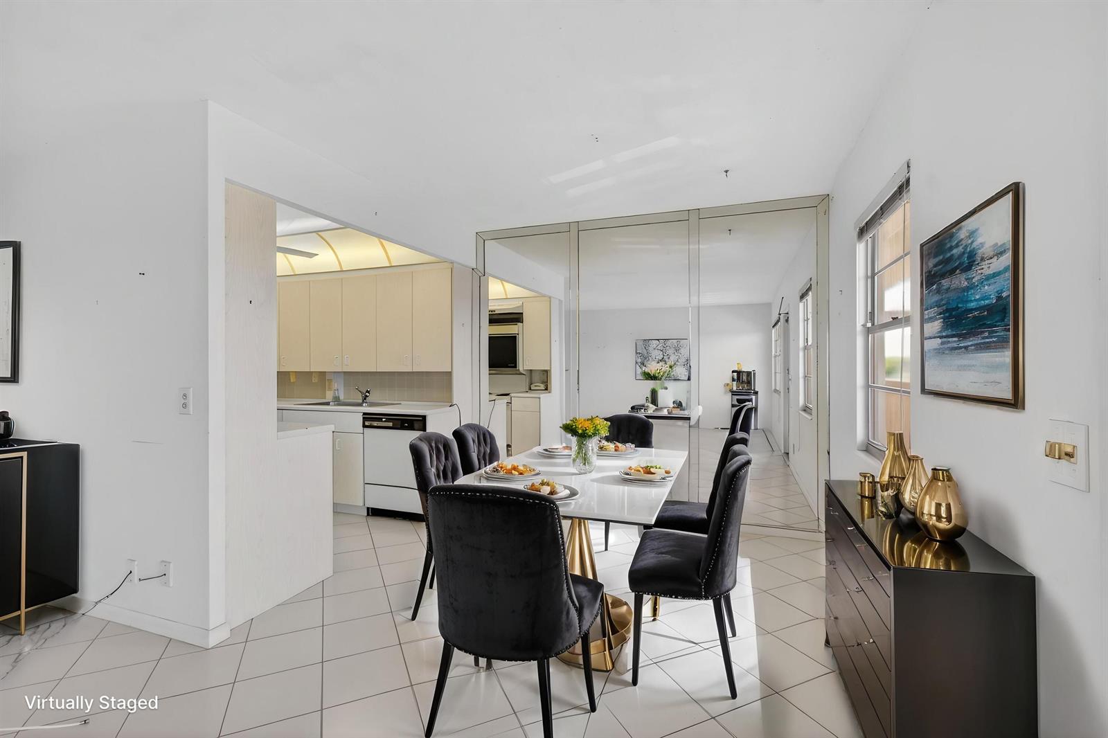 A dining area with a white table, black chairs, and mirrored walls next to a kitchen — 4059 Guildford D, Boca Raton FL 33434, BOCA RATON, FL