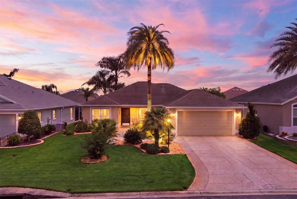 A single-story house with a palm tree in the front yard at sunset — 3335 DALKEITH TERRACE, THE VILLAGES, FL