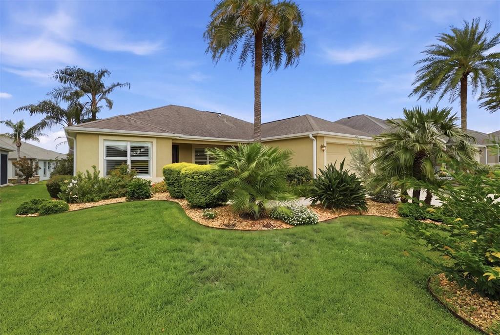 A single-story house with a tan exterior, a shingled roof, and palm trees in the yard — 3335 DALKEITH TERRACE, THE VILLAGES, FL