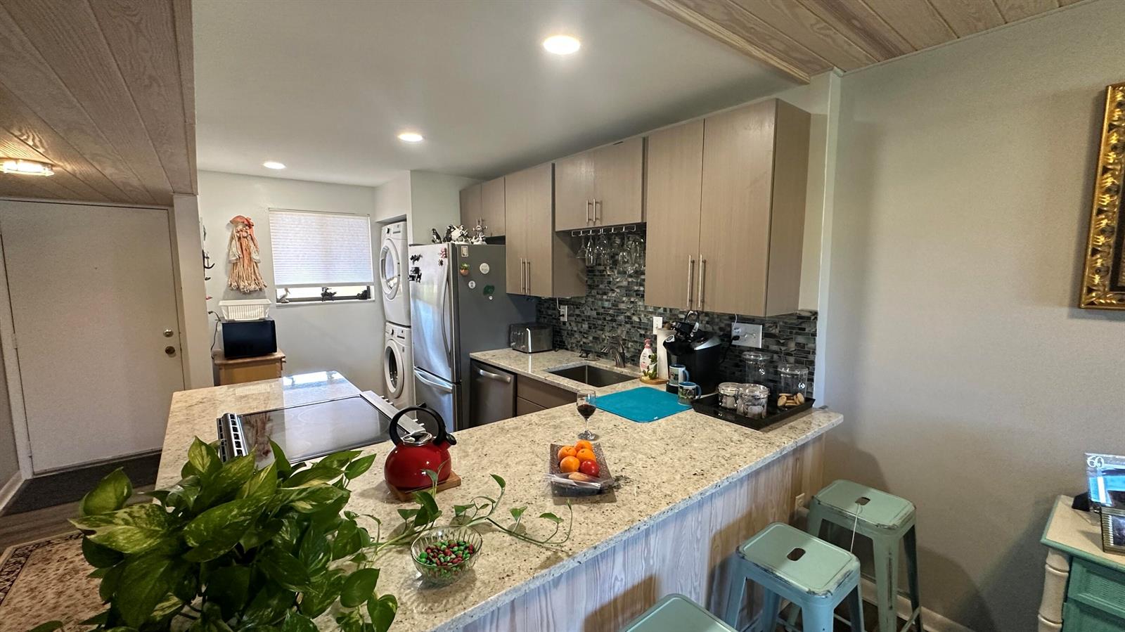 A kitchen features light wood cabinets, granite countertops, a tiled backsplash, and a breakfast bar — 5355 SE Miles Grant Road # 209, Stuart FL 34997, STUART, FL