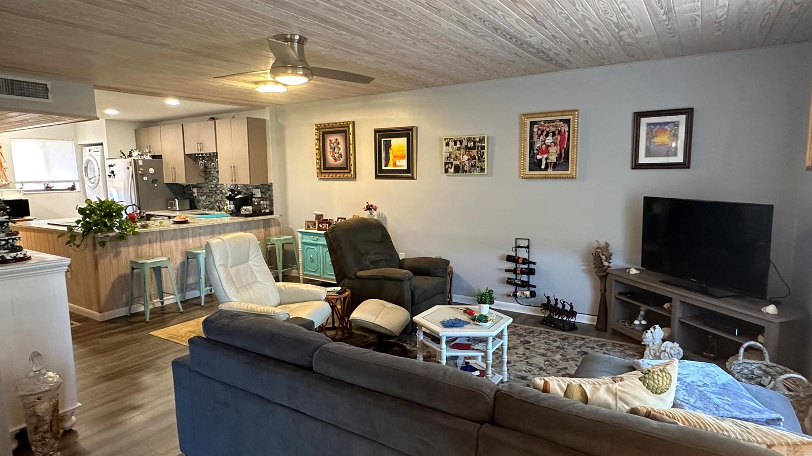 A living room with a sectional sofa, two recliners, and an open kitchen in the background — 5355 SE Miles Grant Road # 209, Stuart FL 34997, STUART, FL