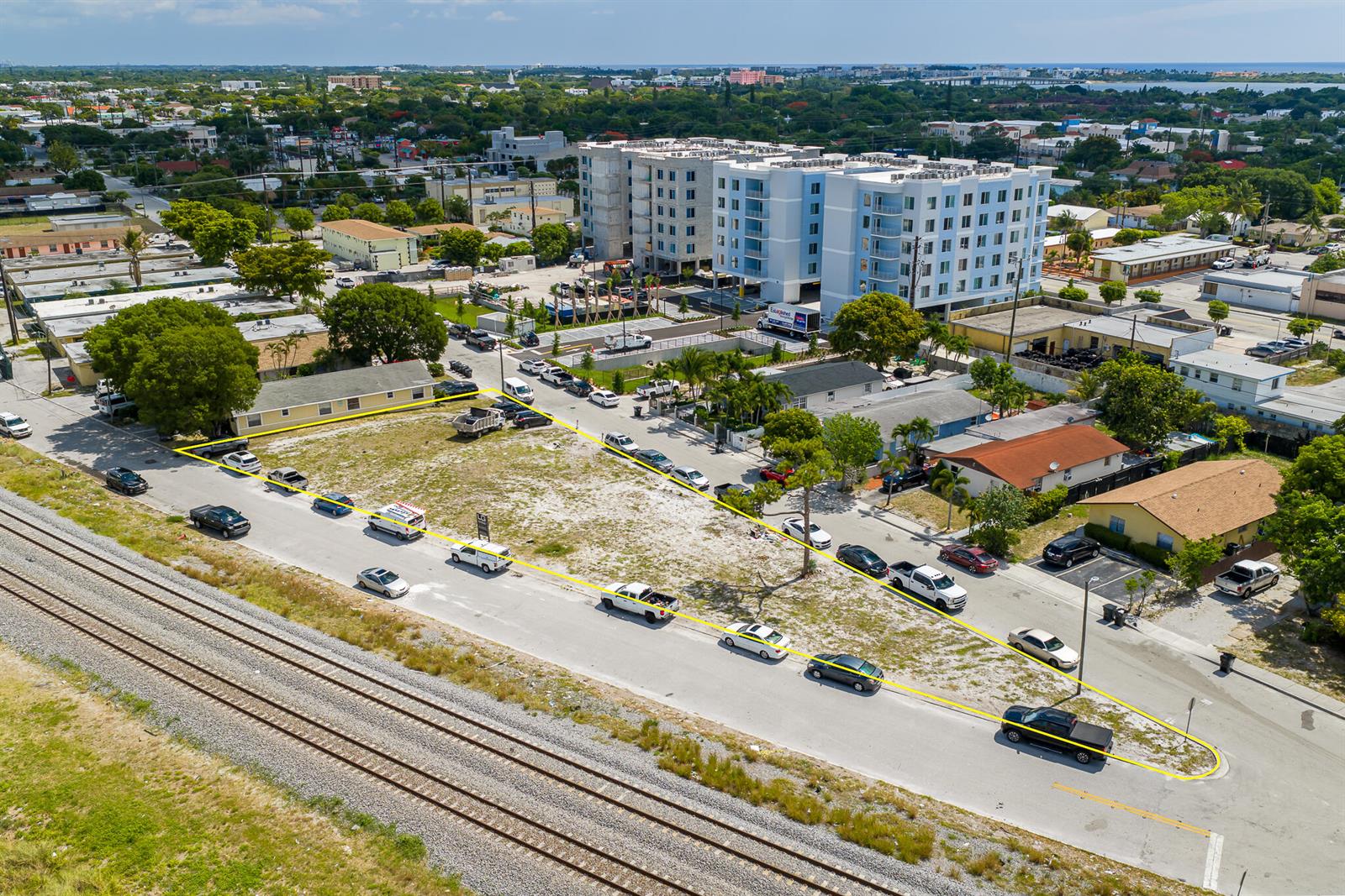 An aerial view shows a vacant, triangular-shaped lot bordered by a road and railroad tracks — 901 S H Street, FL 33460, FL