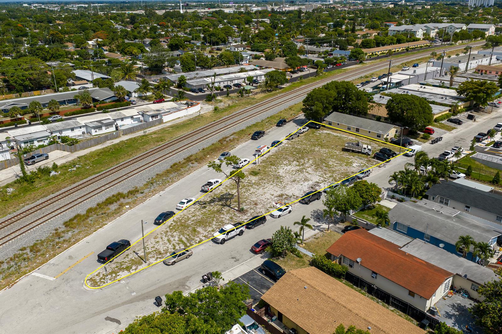 An aerial view shows a vacant rectangular lot outlined in yellow next to railroad tracks — 901 S H Street, FL 33460, FL