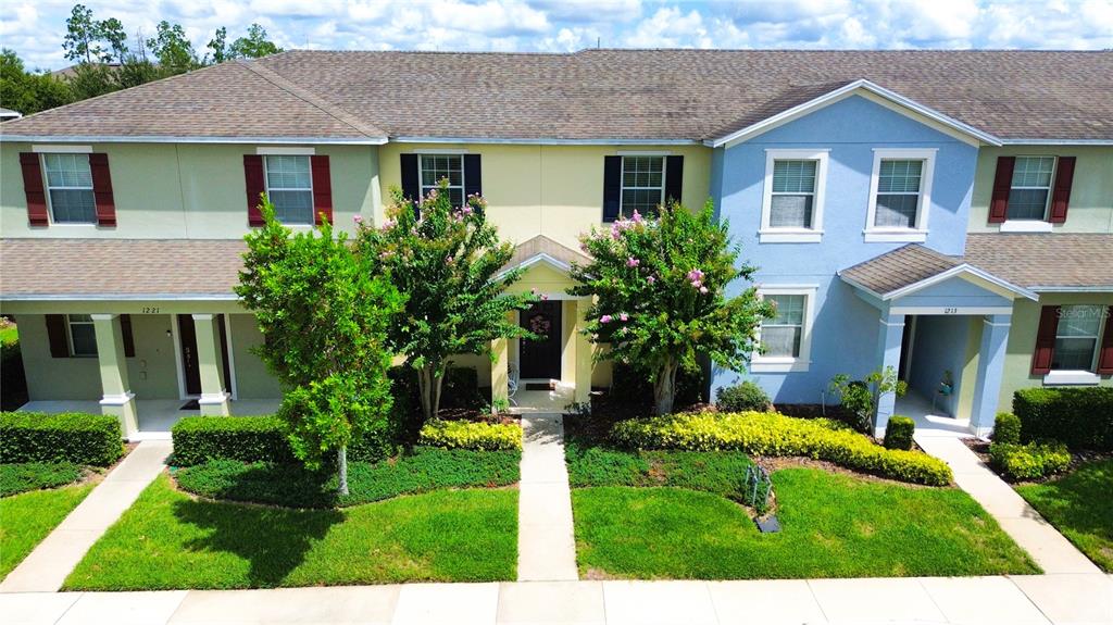 A multi-unit townhouse building features light-colored stucco walls, dark shutters, and manicured landscaping — 1217 SEBURN ROAD, APOPKA, FL