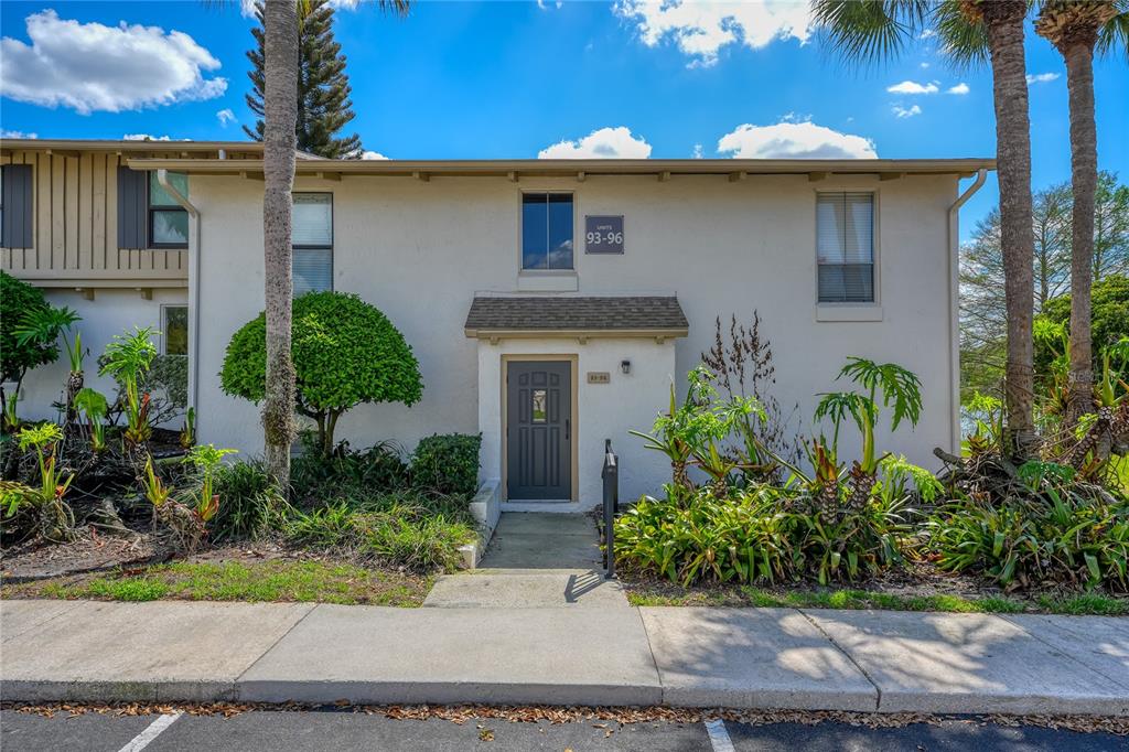 A two-story residential building with a gray front door and a sign labeled 93-96 — 200 MAITLAND AVE UNIT 93, ALTAMONTE SPRINGS, FL