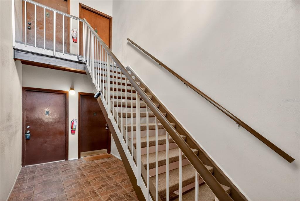 A staircase with carpeted steps and a white metal railing leads to an upper landing — 200 MAITLAND AVE UNIT 93, ALTAMONTE SPRINGS, FL
