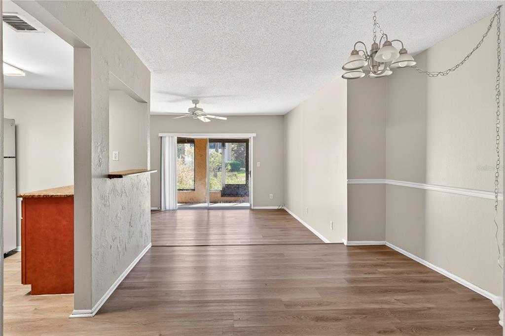 An open-concept living and dining area features wood-look flooring, a ceiling fan, and sliding doors — 200 MAITLAND AVE UNIT 93, ALTAMONTE SPRINGS, FL