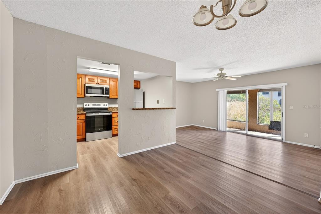 A living room with wood-look flooring, a ceiling fan, and an opening to the kitchen — 200 MAITLAND AVE UNIT 93, ALTAMONTE SPRINGS, FL