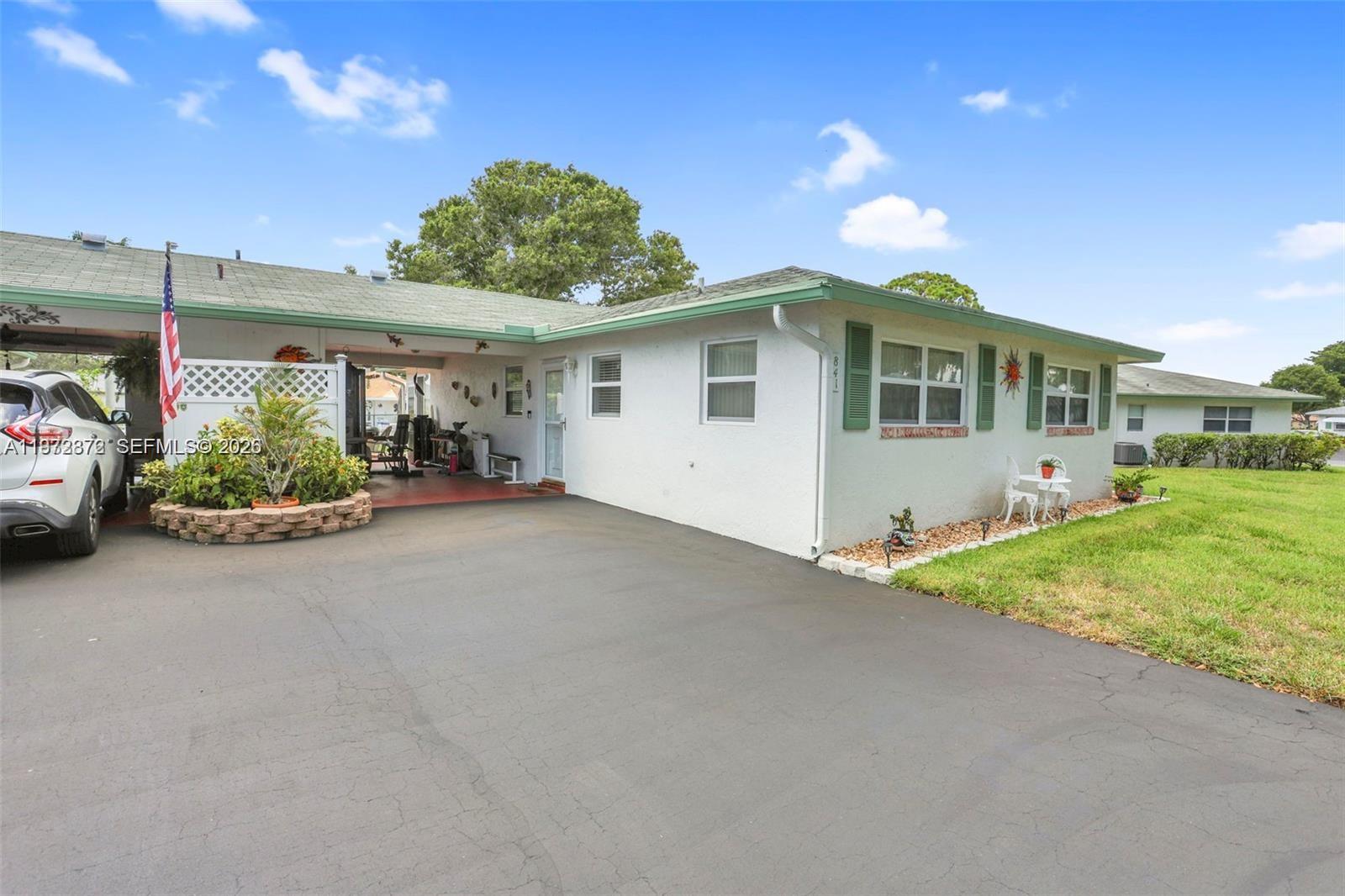 A white single-story house features a carport, a paved driveway, and green window shutters — 841 Meadowlark Ln, Delray Beach FL 33445, DELRAY BEACH, FL