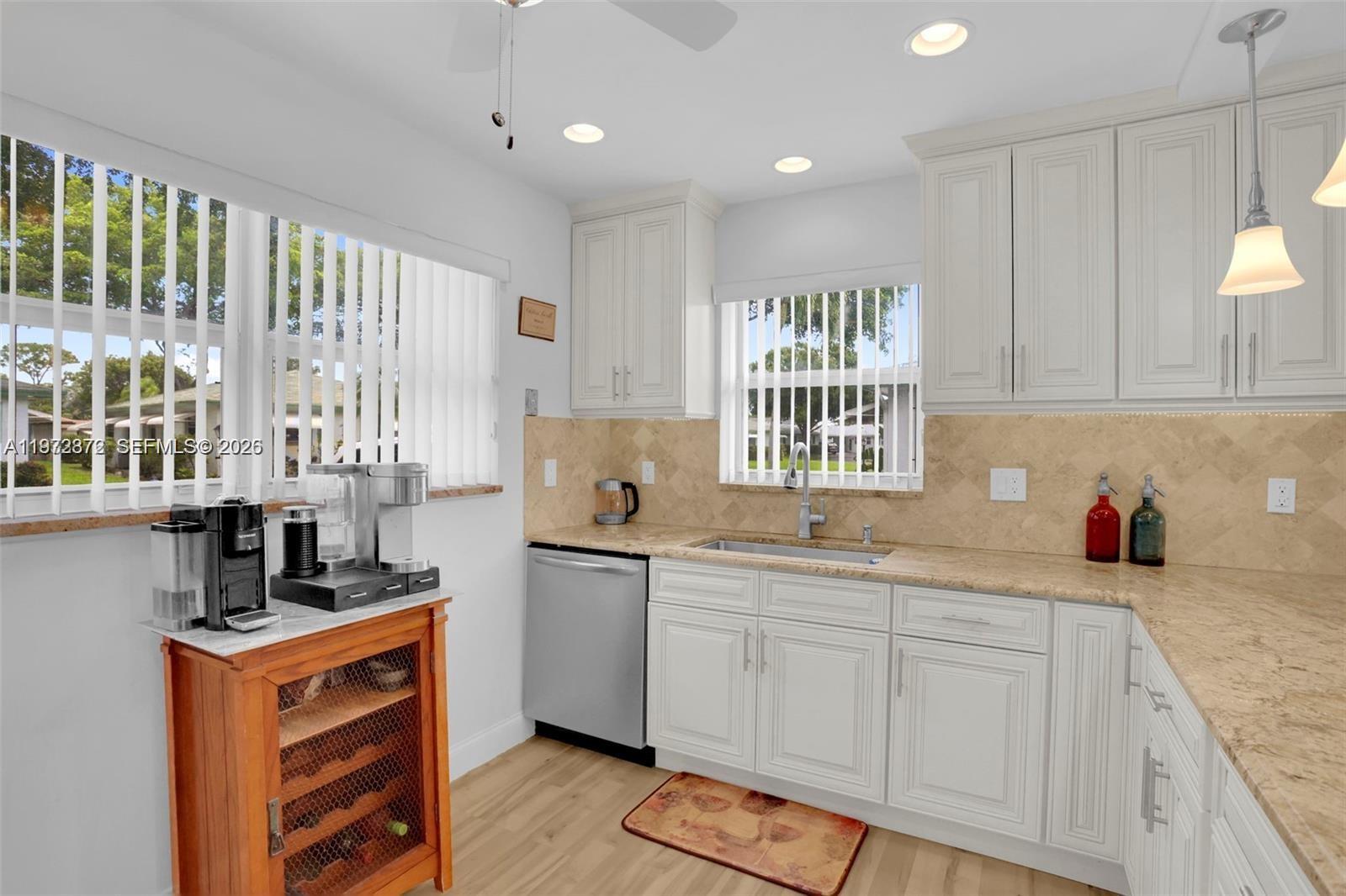 A kitchen features white cabinets, beige countertops, stainless steel appliances, and a wooden wine rack — 841 Meadowlark Ln, Delray Beach FL 33445, DELRAY BEACH, FL