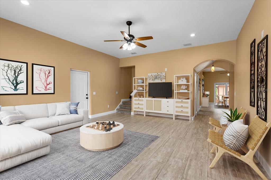 A living room features a white sectional sofa, a round coffee table, and wood-look flooring — 1111 TWIN RIVERS BOULEVARD, OVIEDO, FL
