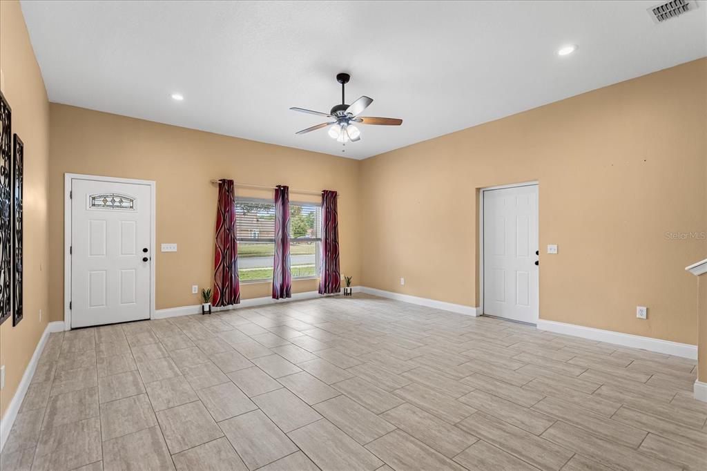 A living room with tan walls, light wood-look tile flooring, and a ceiling fan — 1111 TWIN RIVERS BOULEVARD, OVIEDO, FL