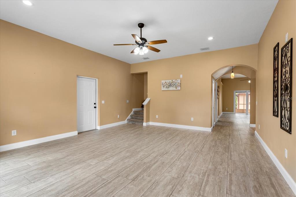 A spacious room with tan walls, light wood-look tile flooring, and a ceiling fan — 1111 TWIN RIVERS BOULEVARD, OVIEDO, FL