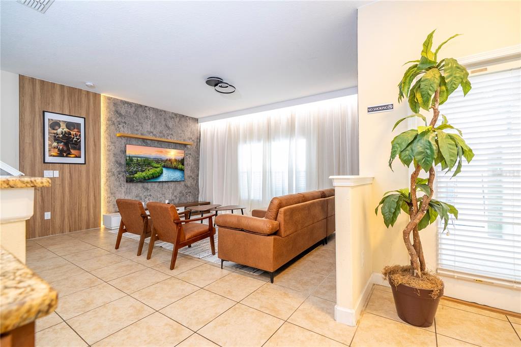 A living room features a textured accent wall, a television, and brown leather furniture — 8935 CANDY PALM ROAD, KISSIMMEE, FL