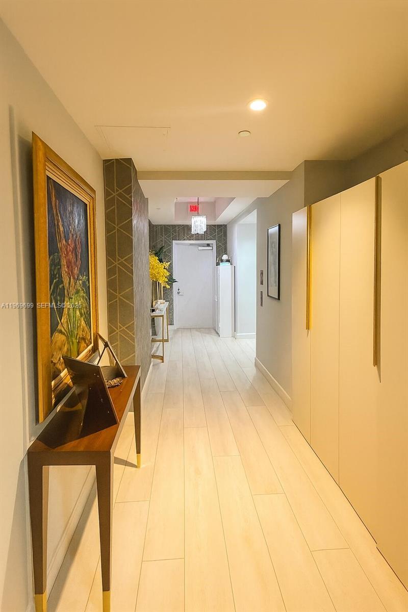 A hallway features light wood flooring, a framed painting, a console table, and floor-to-ceiling cabinets — 851 NE 1st Ave # 2212, Miami FL 33132, MIAMI, FL