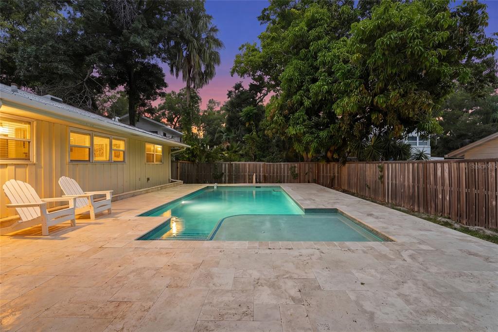 A backyard features a rectangular swimming pool with a tanning ledge surrounded by stone pavers — 2480 ALAMEDA AVENUE, SARASOTA, FL