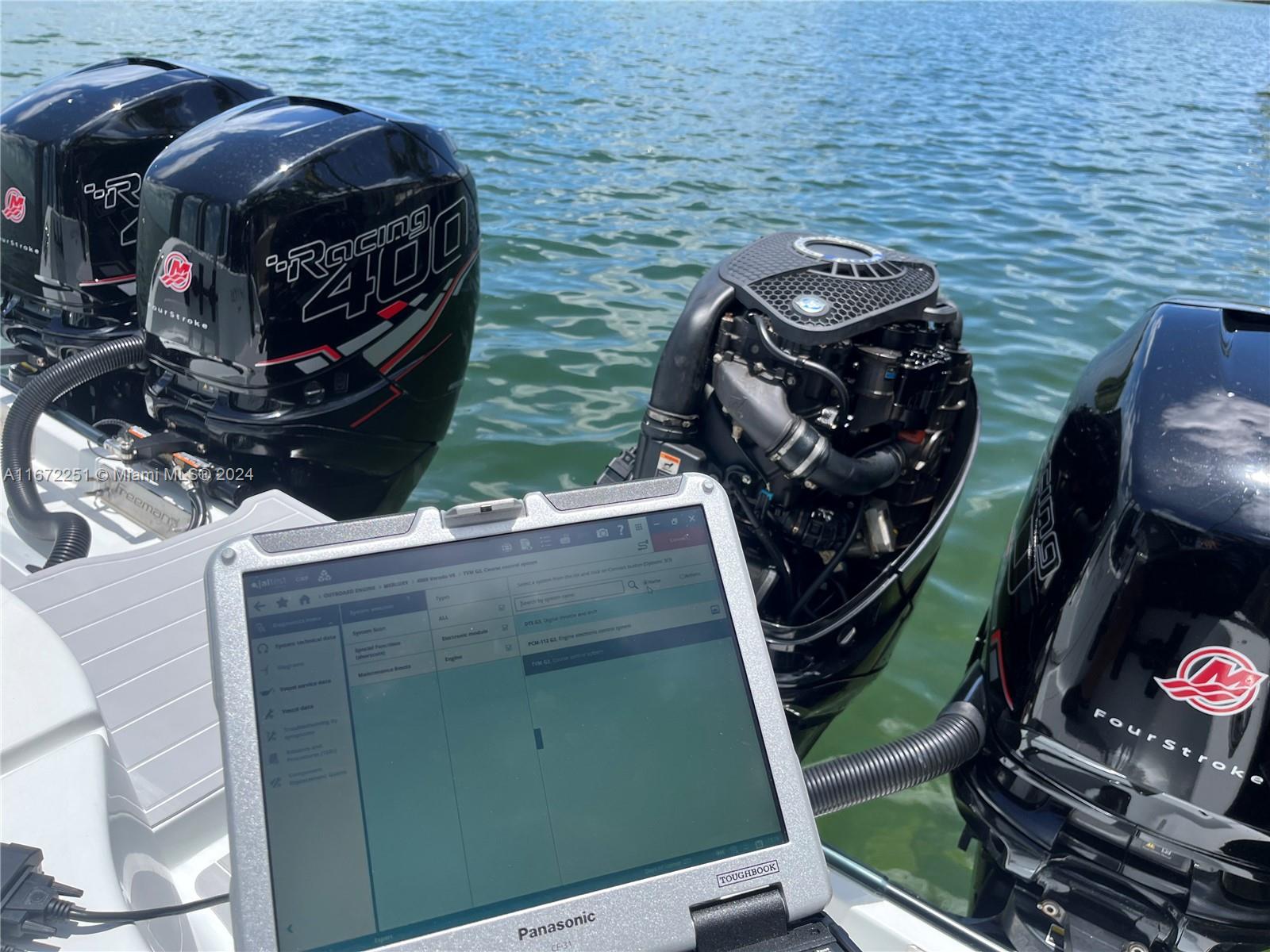A diagnostic laptop sits on the stern of a boat with four Mercury outboard motors — 101425 Overseas Highway, Key Largo FL 33037, KEY LARGO, FL