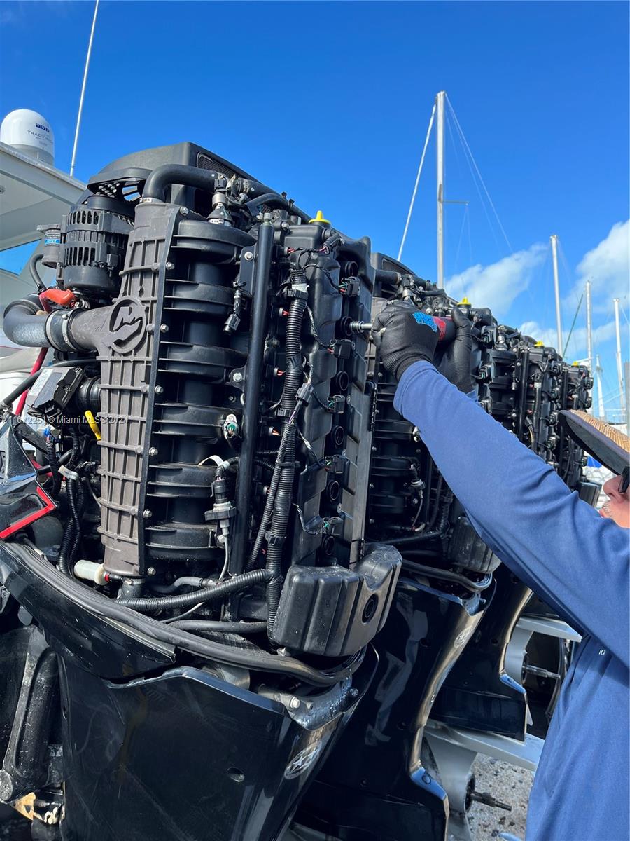 A mechanic works on the exposed engine of a boat parked outdoors — 101425 Overseas Highway, Key Largo FL 33037, KEY LARGO, FL