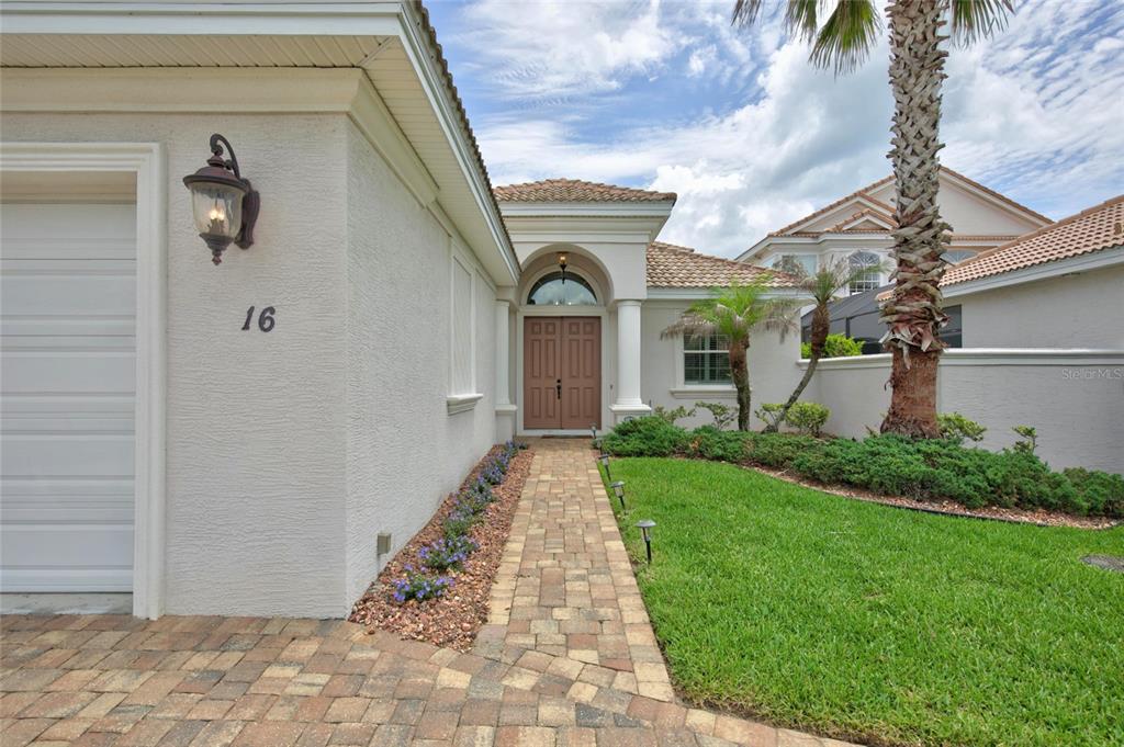 A paved walkway leads to the front entrance of a house with a garage — 16 MONTILLA PLACE, PALM COAST, FL