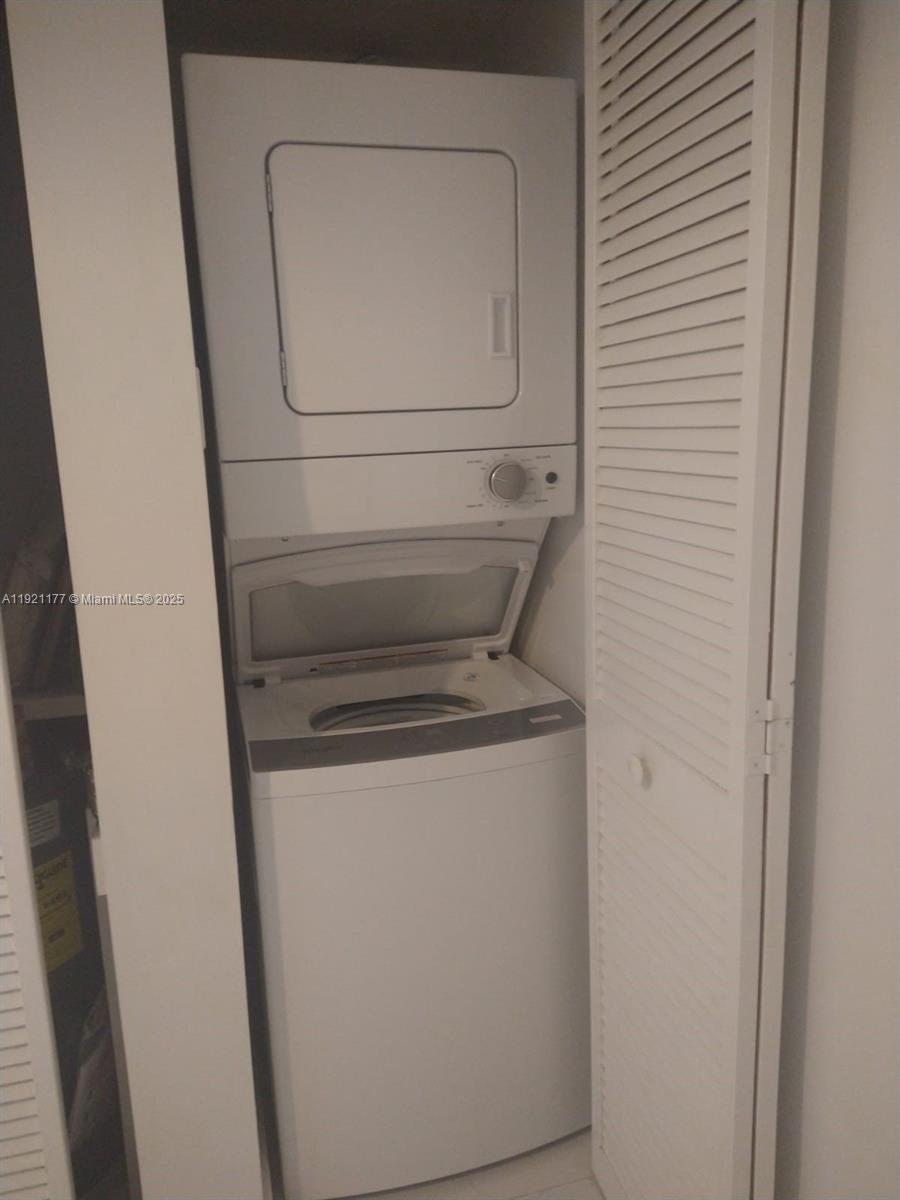 A white stacked washer and dryer unit is located inside a closet with louvered doors — 9341 SE Collins Ave # 303, Surfside FL 33154, SURFSIDE, FL