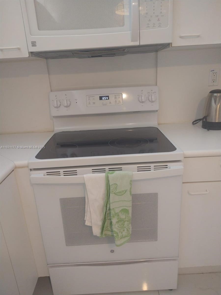 A white electric range with a glass cooktop sits below a matching over-the-range microwave — 9341 SE Collins Ave # 303, Surfside FL 33154, SURFSIDE, FL