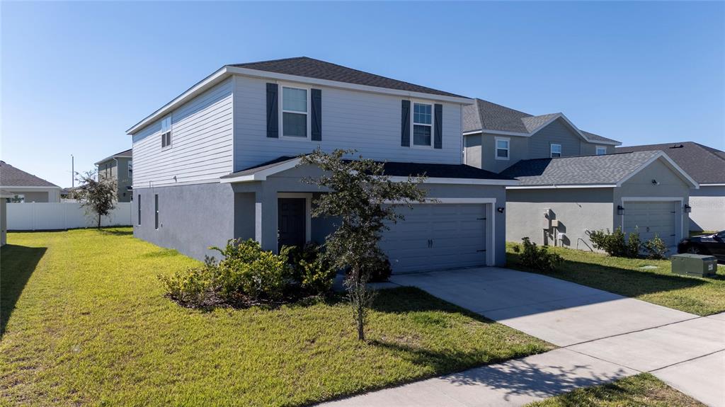 A two-story house with light gray siding, a gray garage, and a front lawn — 419 LILY LANE, DAVENPORT, FL