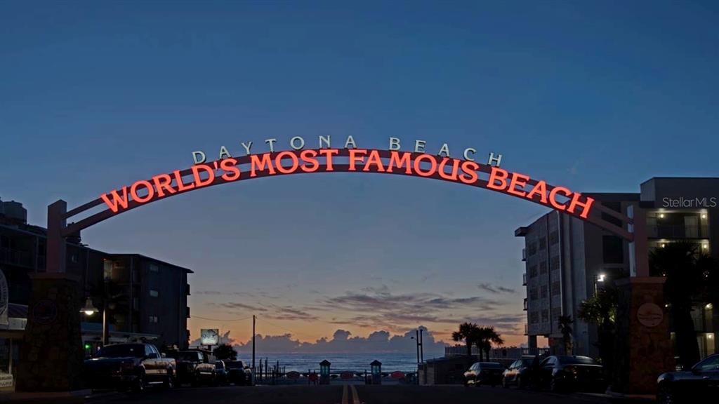 An illuminated archway spans a street leading to the ocean at sunrise in Daytona Beach — 219 S ATLANTIC AVENUE UNIT 237, DAYTONA BEACH, FL