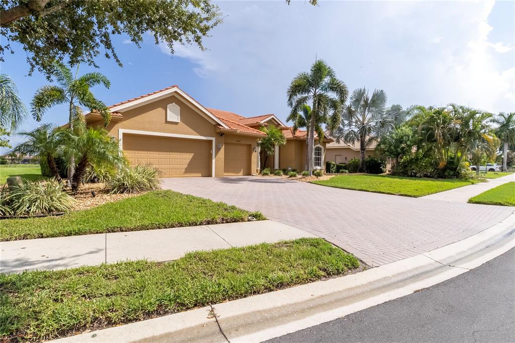 A tan single-story house with a tile roof and a paved driveway in a neighborhood — 12709 PENGUIN DRIVE, BRADENTON, FL