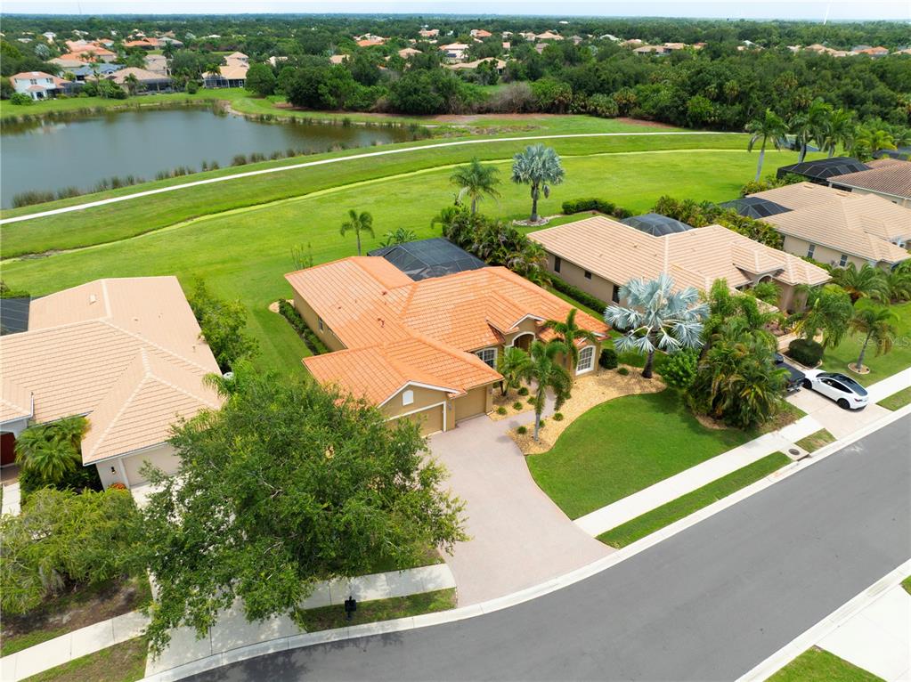 An aerial view shows a suburban house with a tile roof, driveway, and backyard pool — 12709 PENGUIN DRIVE, BRADENTON, FL
