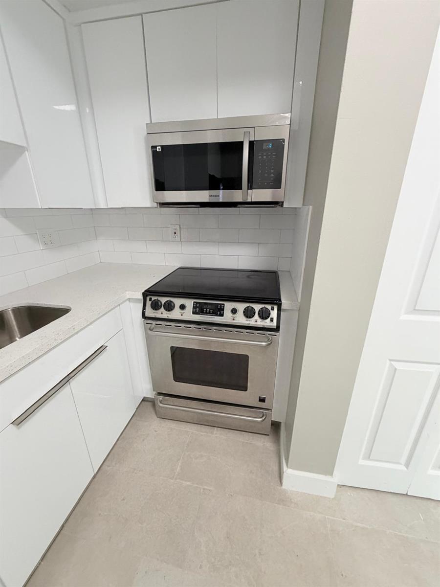 A kitchen features white cabinets, stainless steel appliances, a subway tile backsplash, and quartz countertops — 1390 W 37th Street # 101, Hialeah FL 33012, HIALEAH, FL