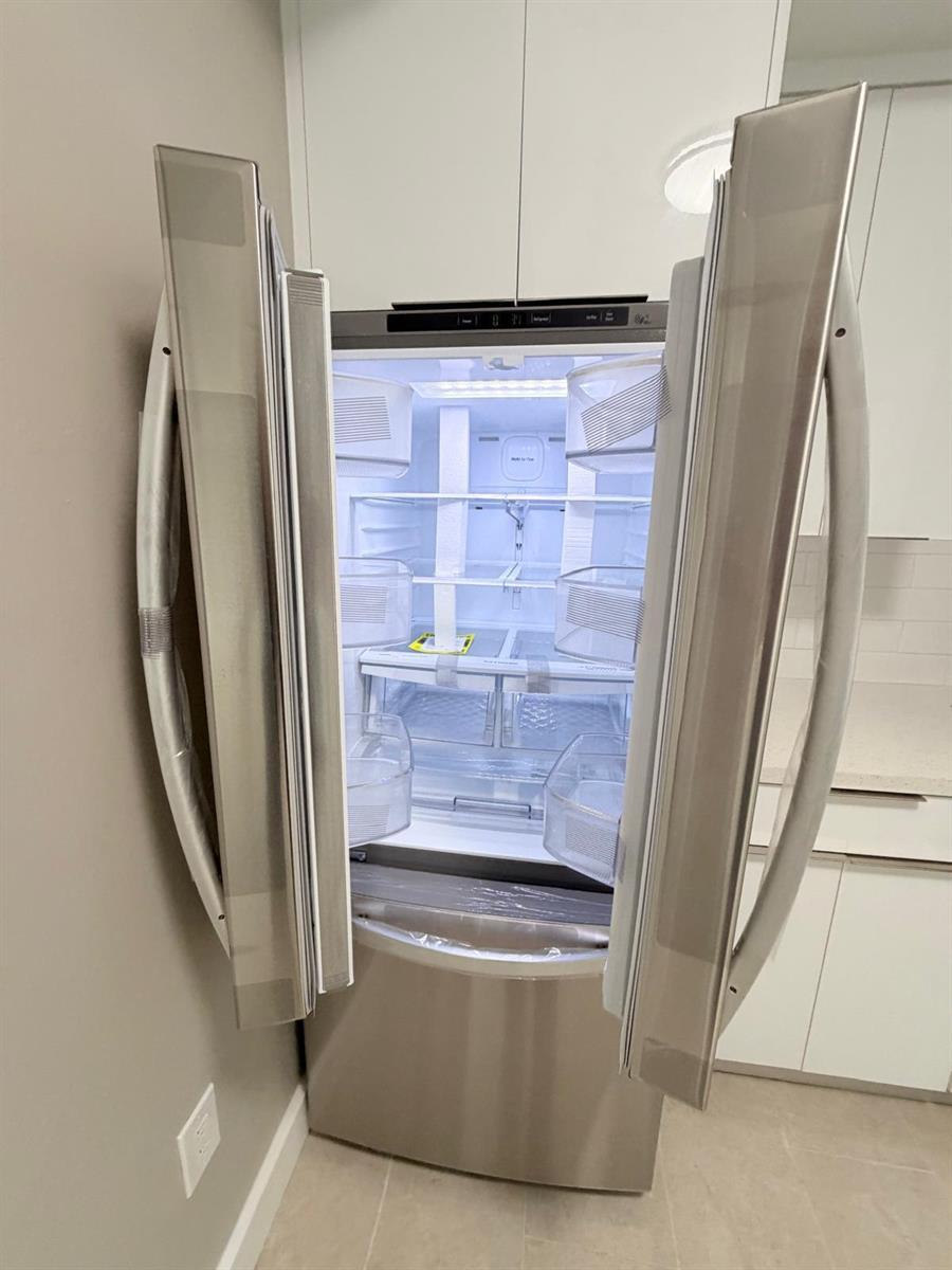 A stainless steel French door refrigerator stands open in a modern kitchen with white cabinets — 1390 W 37th Street # 101, Hialeah FL 33012, HIALEAH, FL