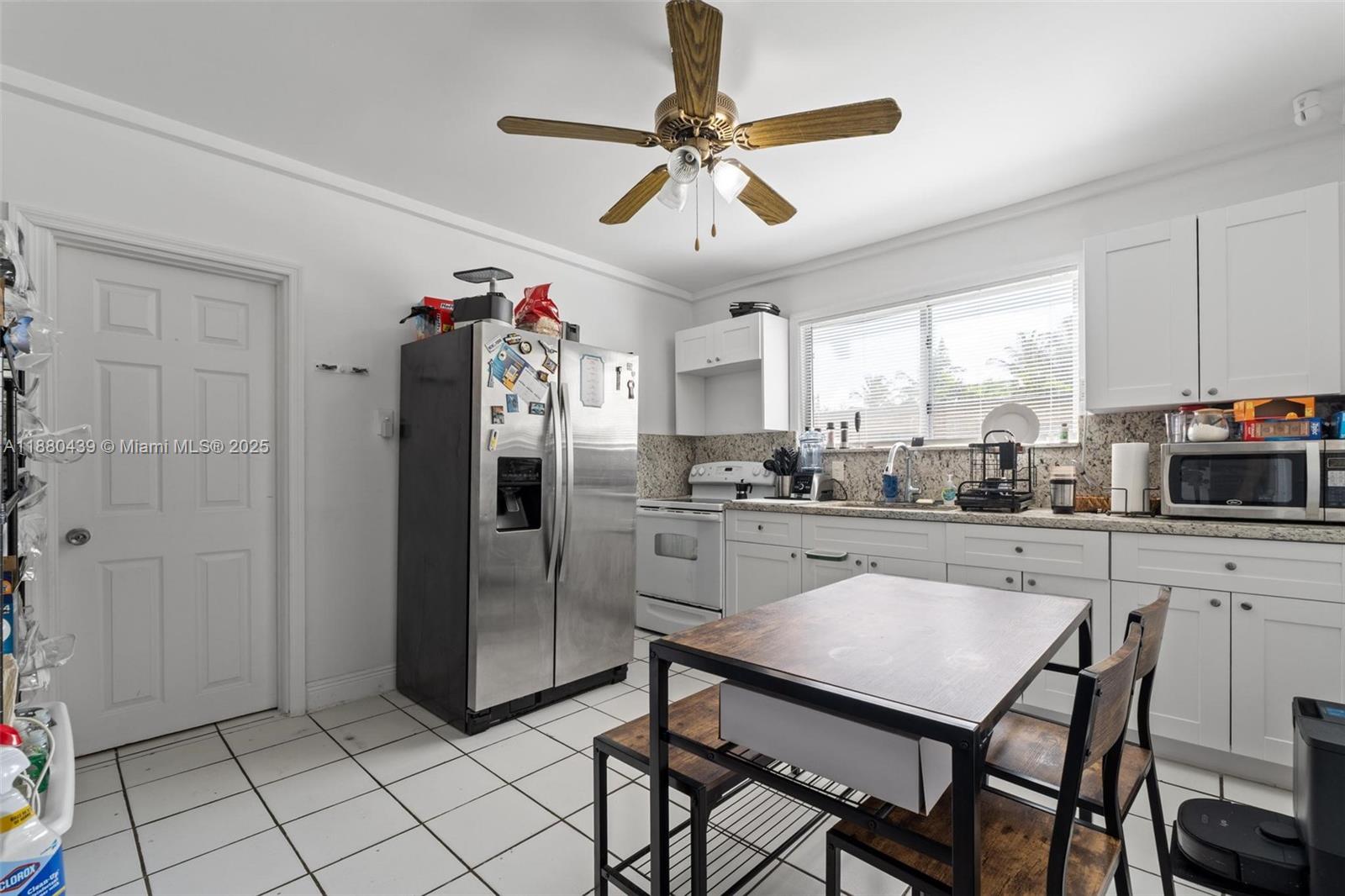 A kitchen features white cabinets, stainless steel appliances, a dining table, and tiled flooring — 2453 SW 17th St # 2, Miami FL 33145, MIAMI, FL