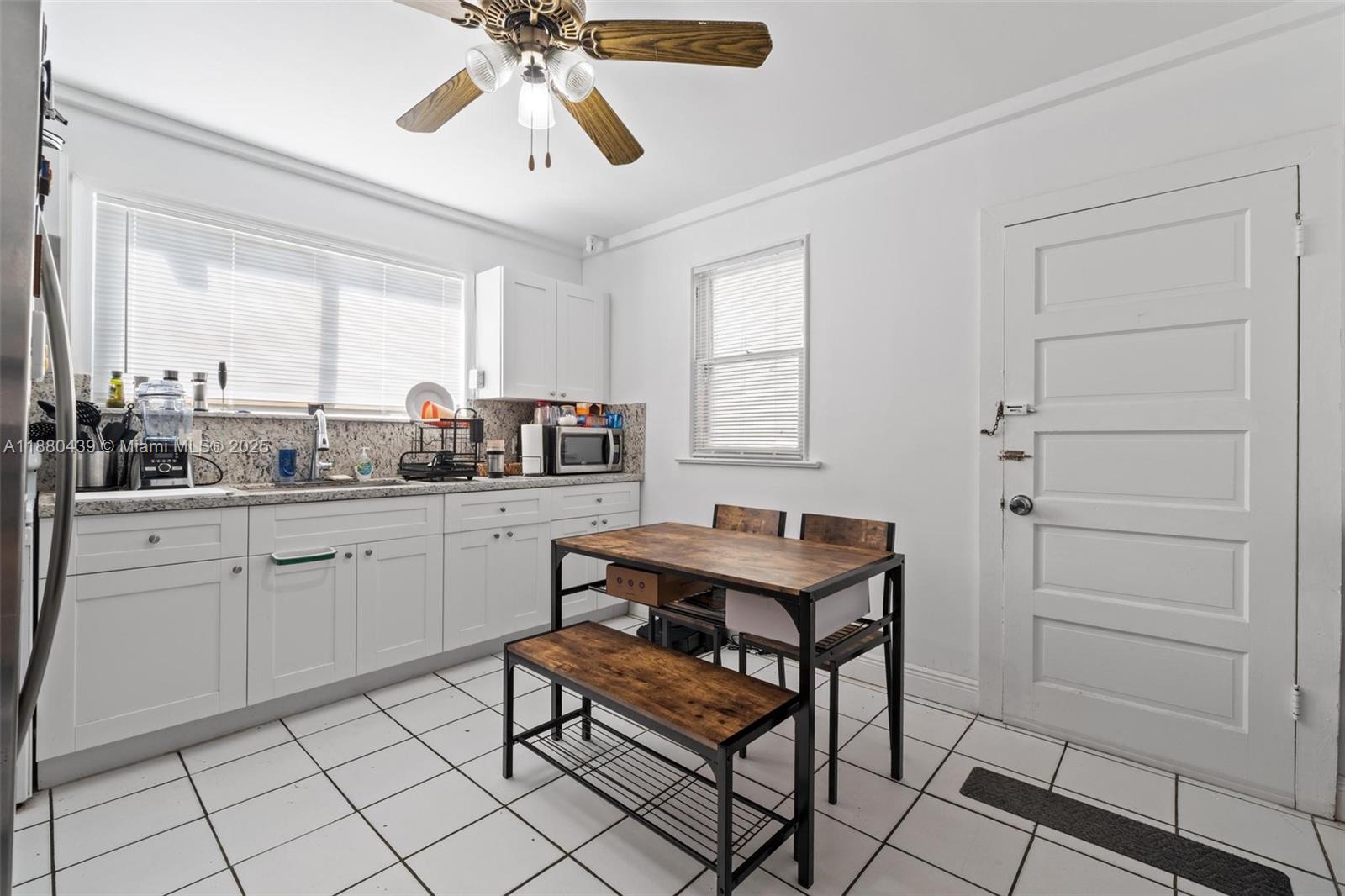 A kitchen features white cabinets, granite countertops, a dining table with benches, and tile flooring — 2453 SW 17th St # 2, Miami FL 33145, MIAMI, FL