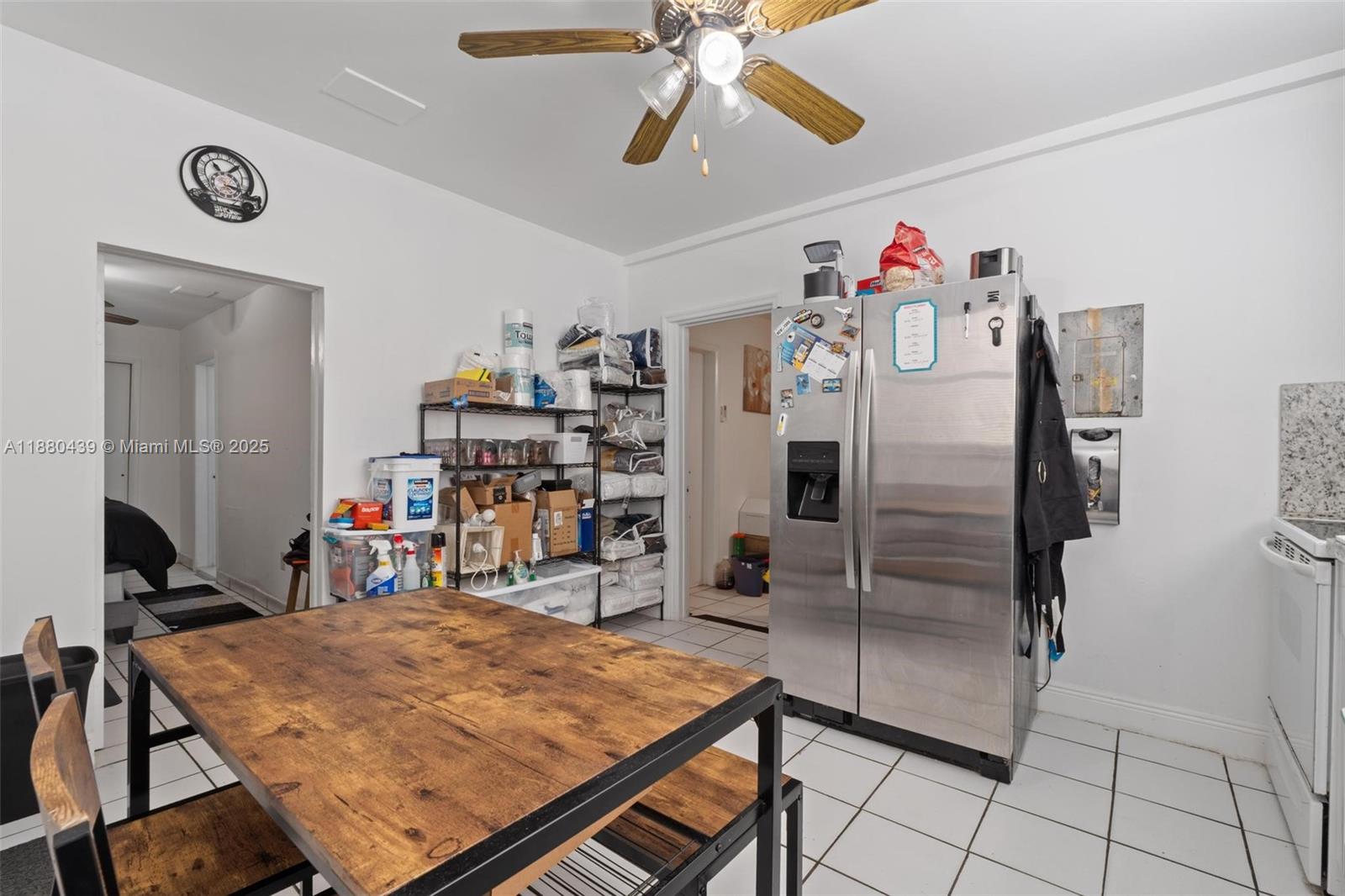 A kitchen features a dining table, a stainless steel refrigerator, and metal shelving units — 2453 SW 17th St # 2, Miami FL 33145, MIAMI, FL