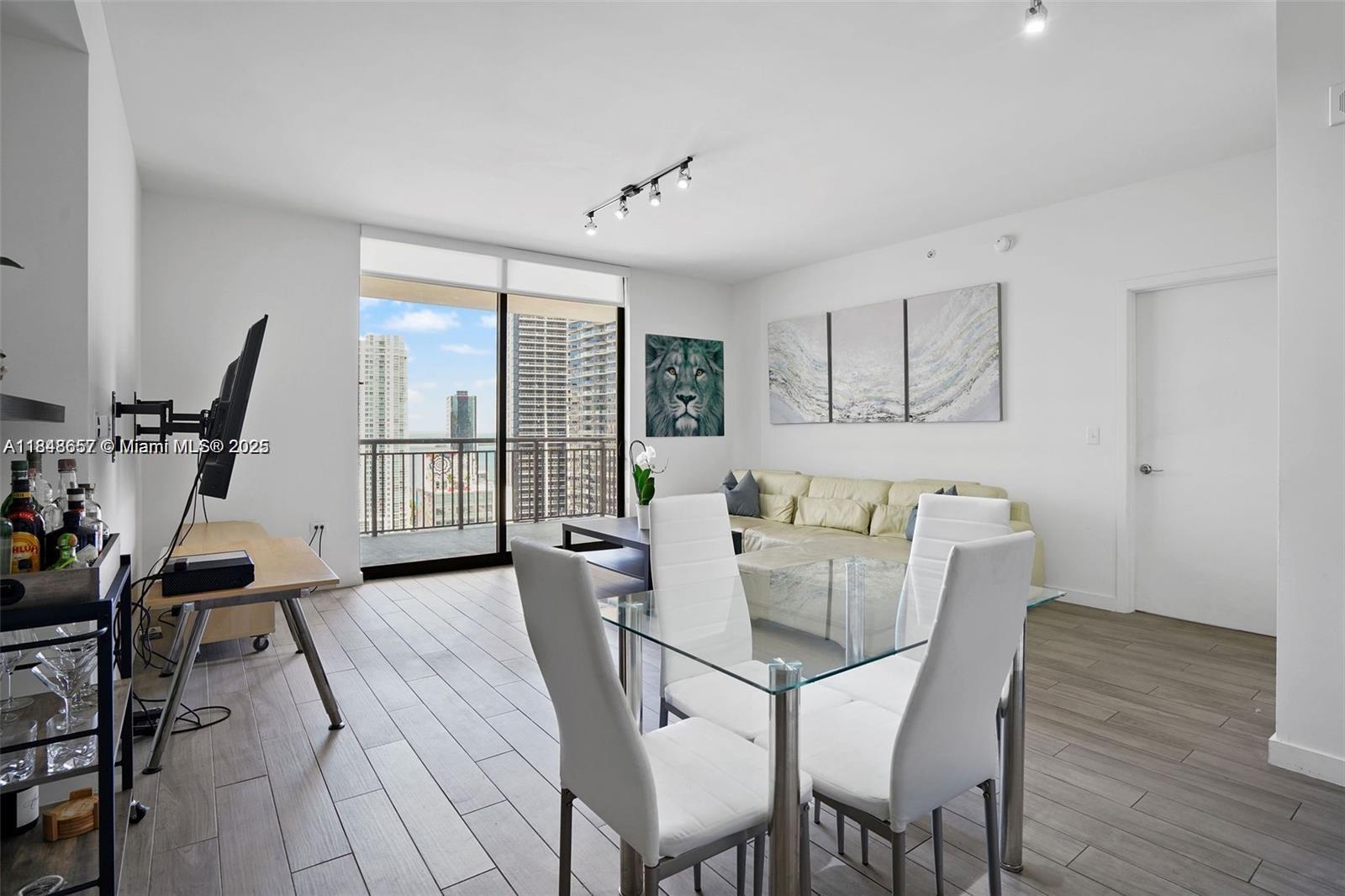 A modern living and dining area features white walls, tile floors, and a balcony view — 999 SW 1st Ave # 2717, Miami FL 33130, MIAMI, FL