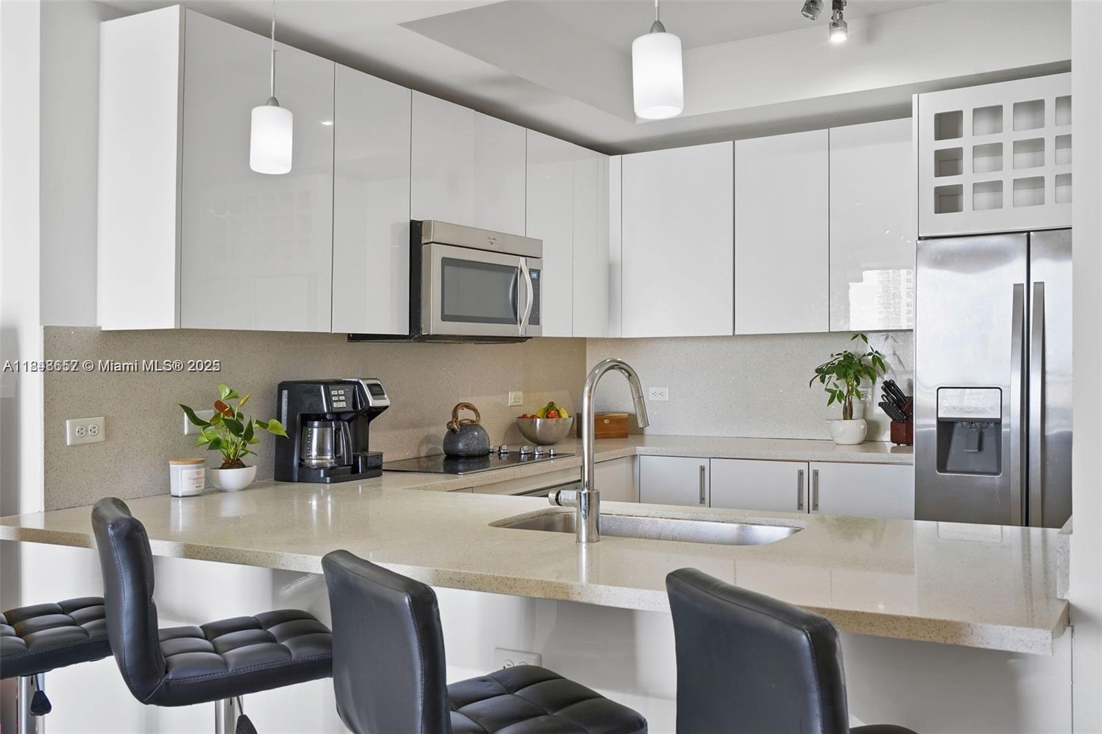 A modern kitchen features white cabinets, stainless steel appliances, and a quartz breakfast bar — 999 SW 1st Ave # 2717, Miami FL 33130, MIAMI, FL