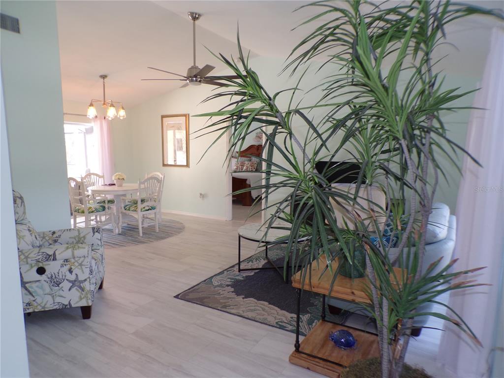A living and dining area features light wood-look flooring, a ceiling fan, and a large plant — 15624 HENNIPEN CIRCLE, PORT CHARLOTTE, FL