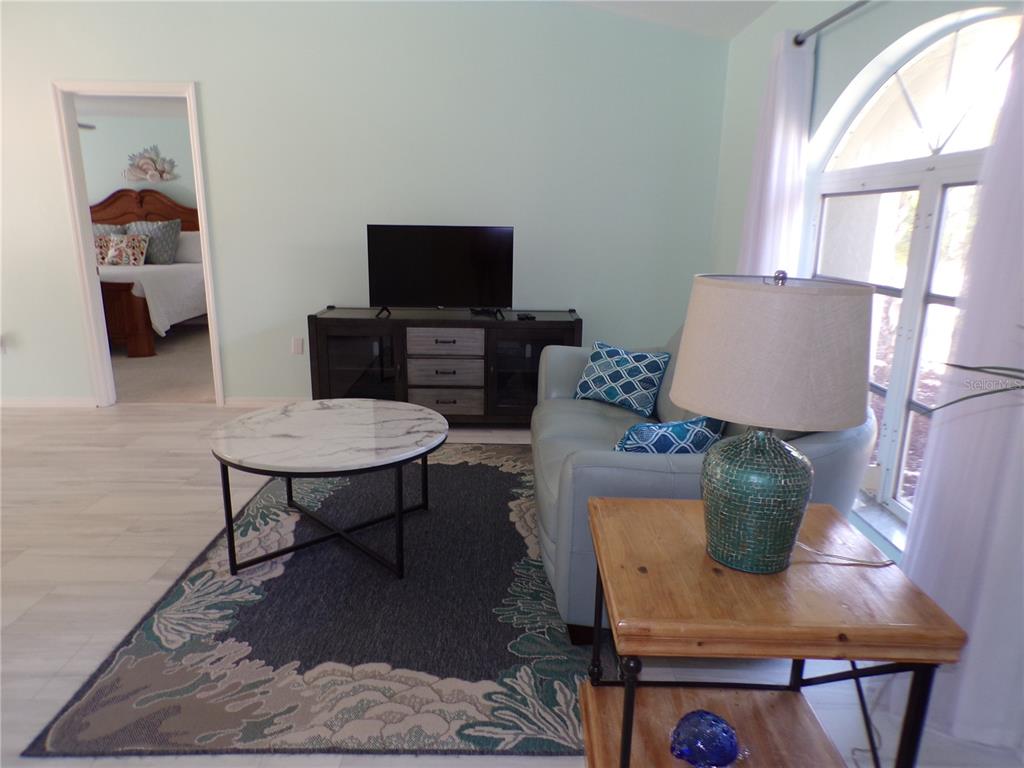A living room features a light blue sofa, a marble coffee table, and a television console — 15624 HENNIPEN CIRCLE, PORT CHARLOTTE, FL