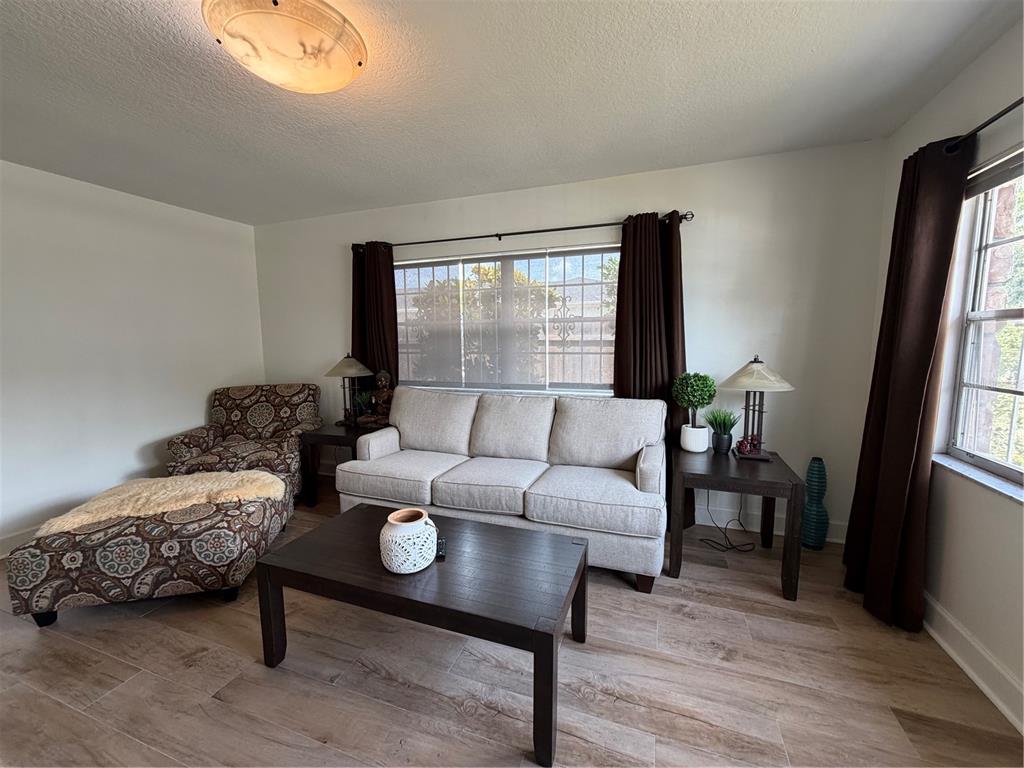 A living room features a light-colored sofa, patterned armchair, dark wood furniture, and tile flooring — 3230 W SAINT CONRAD STREET, TAMPA, FL