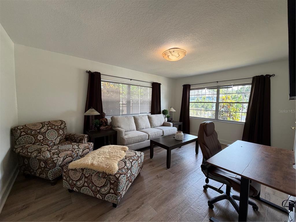A living room features a patterned armchair with ottoman, a sofa, and a desk area — 3230 W SAINT CONRAD STREET, TAMPA, FL
