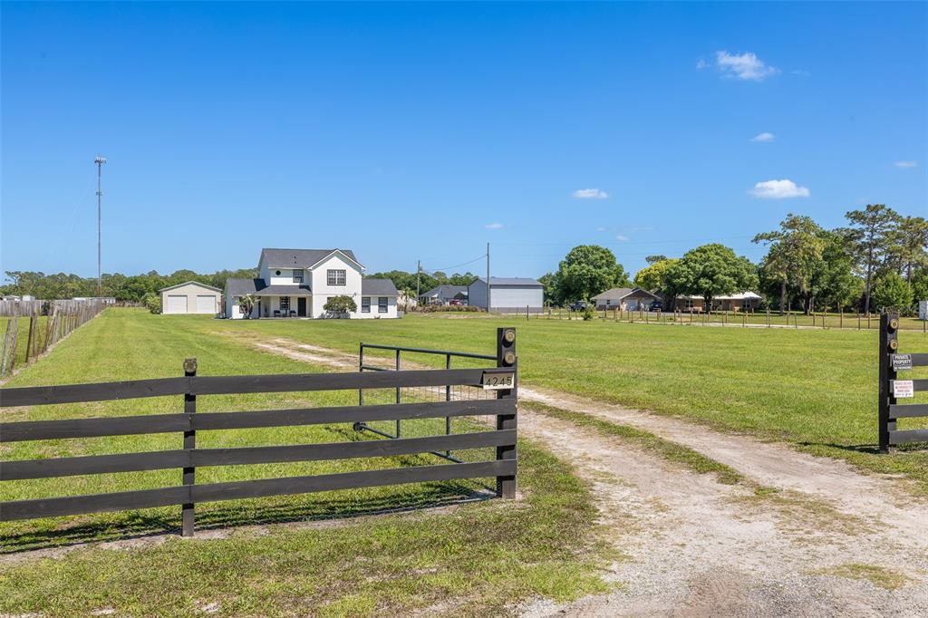 A white two-story house sits on a large grassy lot behind a wooden fence — 4245 HENRY J AVENUE, ST CLOUD, FL