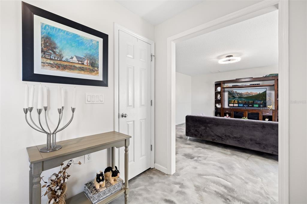 A foyer with a console table and artwork leads into a living room with a television — 4245 HENRY J AVENUE, ST CLOUD, FL